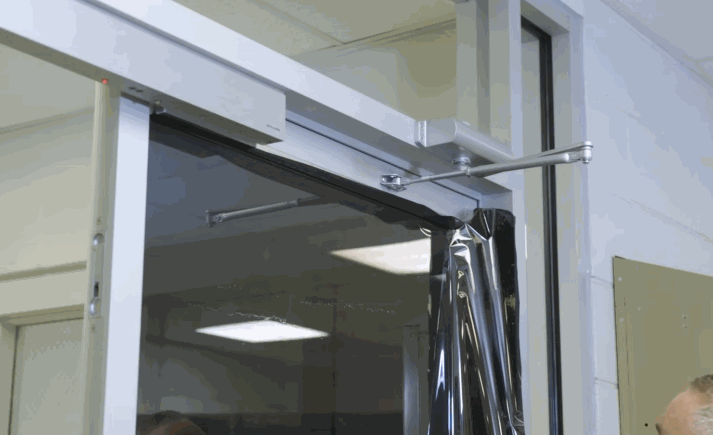 A step-by-step GIF showing the installation of a window film on a glass door, highlighting the application process and equipment used